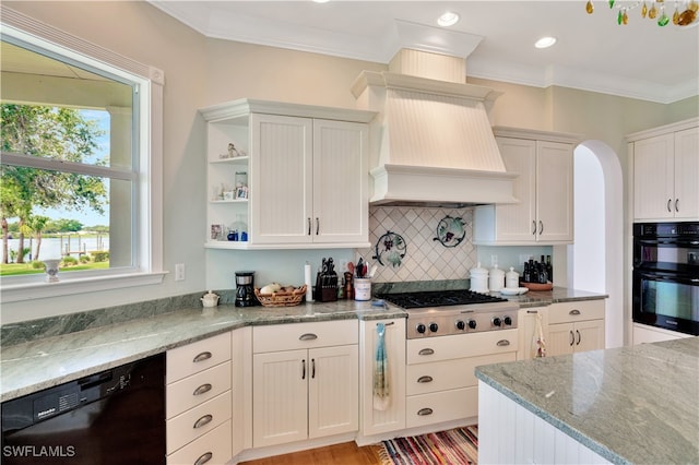 kitchen with light stone countertops, backsplash, ornamental molding, black appliances, and white cabinetry