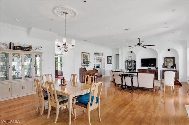 dining area with ceiling fan with notable chandelier, light hardwood / wood-style flooring, and crown molding