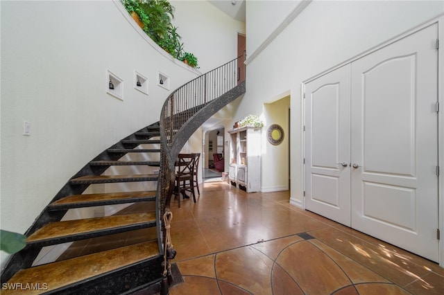 stairway with tile patterned flooring and a towering ceiling