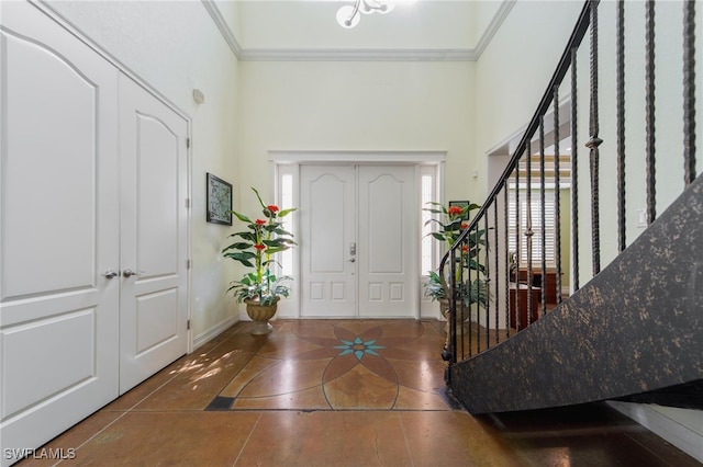 tiled entrance foyer with crown molding, a towering ceiling, and a healthy amount of sunlight