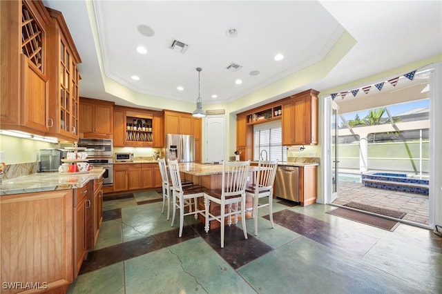 kitchen featuring a center island, a kitchen breakfast bar, a raised ceiling, hanging light fixtures, and stainless steel appliances