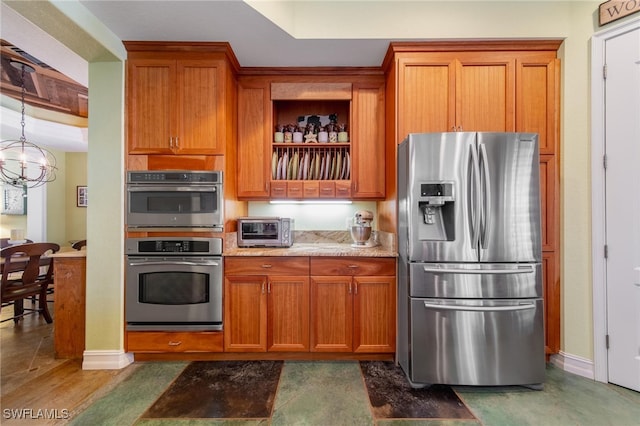 kitchen with dark hardwood / wood-style flooring, light stone counters, appliances with stainless steel finishes, and a chandelier