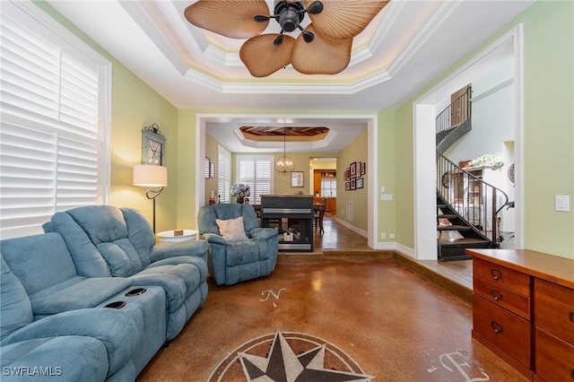 living room featuring a tray ceiling, ceiling fan, and crown molding