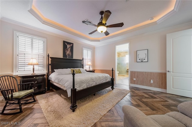 bedroom with dark parquet flooring, ensuite bathroom, a tray ceiling, ceiling fan, and crown molding