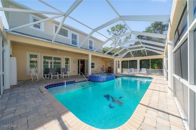 view of pool featuring glass enclosure, an in ground hot tub, ceiling fan, and a patio