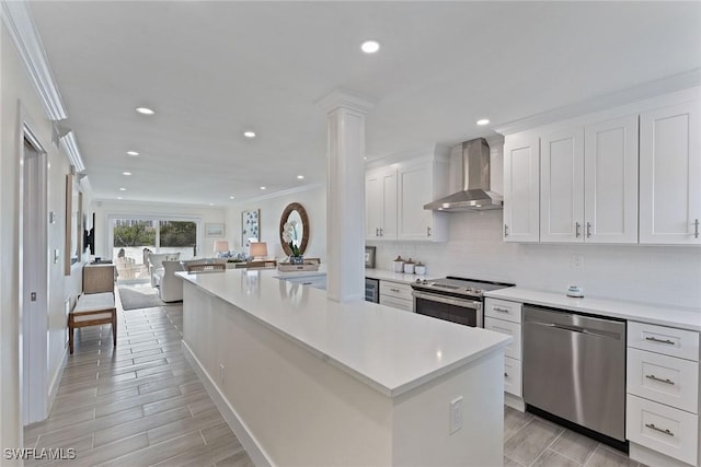 kitchen with a center island, white cabinets, wall chimney exhaust hood, appliances with stainless steel finishes, and tasteful backsplash