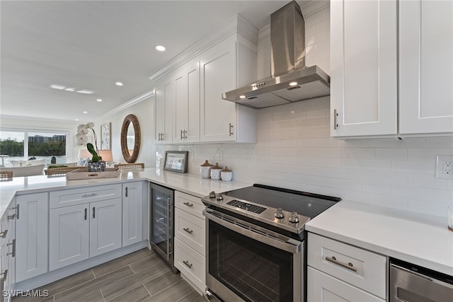 kitchen featuring backsplash, wall chimney exhaust hood, beverage cooler, electric stove, and white cabinets