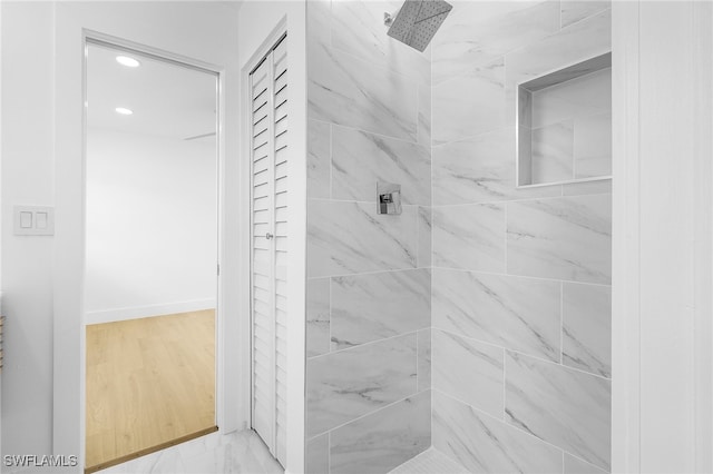 bathroom with a tile shower and hardwood / wood-style flooring