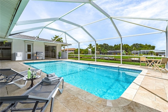 view of swimming pool with area for grilling, a patio, and glass enclosure