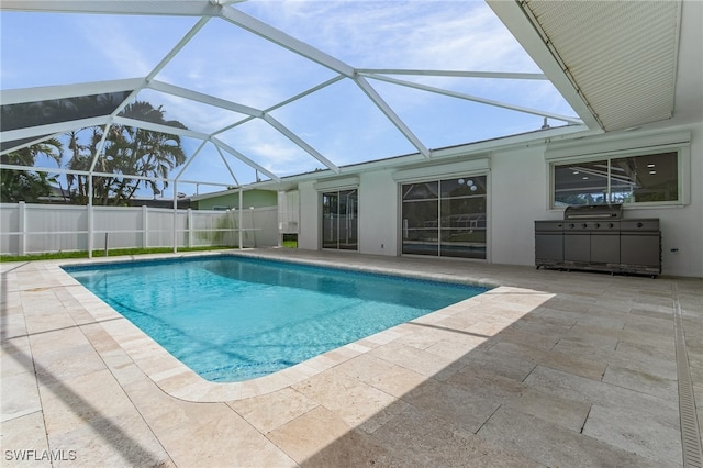 view of pool featuring glass enclosure, a patio, and an outdoor kitchen