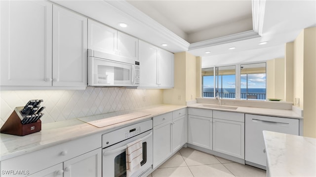 kitchen with white cabinetry, sink, a water view, and white appliances