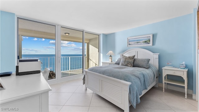 tiled bedroom with access to exterior, a water view, and floor to ceiling windows