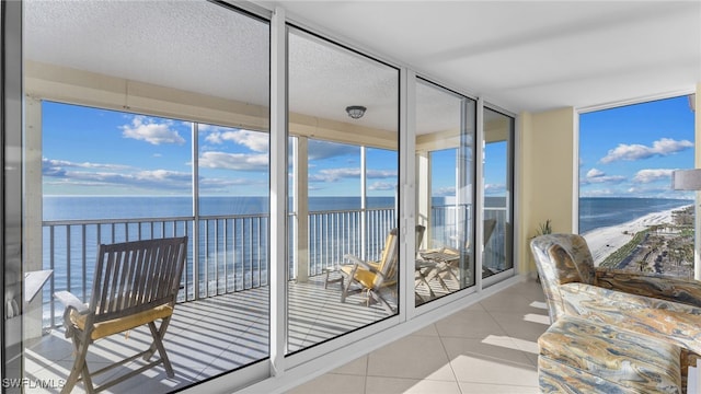 sunroom featuring a view of the beach and a water view