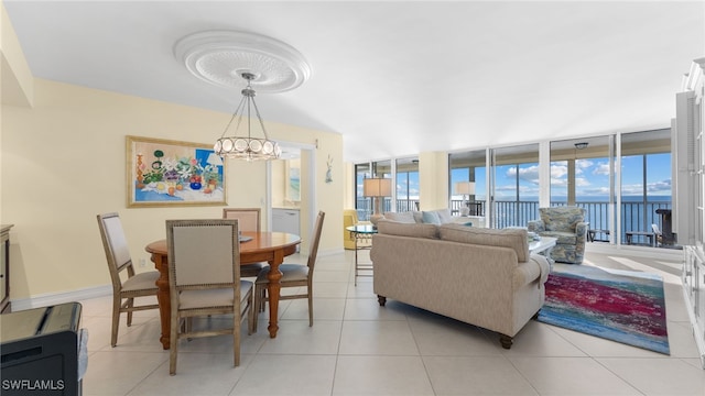 living room with expansive windows, a water view, light tile patterned floors, and an inviting chandelier