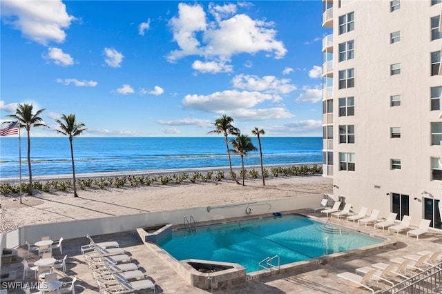 view of swimming pool featuring a water view and a beach view