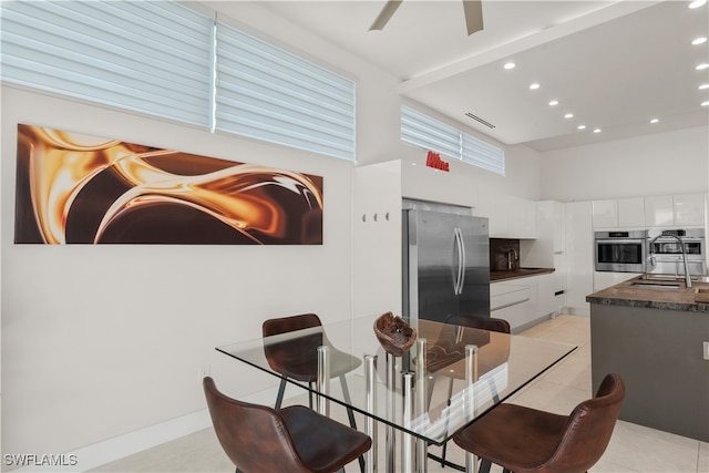 kitchen with sink, white cabinets, a high ceiling, stainless steel refrigerator, and light tile patterned flooring