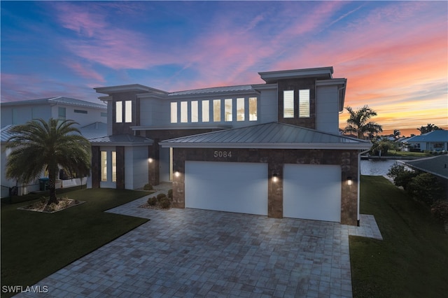 view of front of property featuring a yard, a water view, and a garage