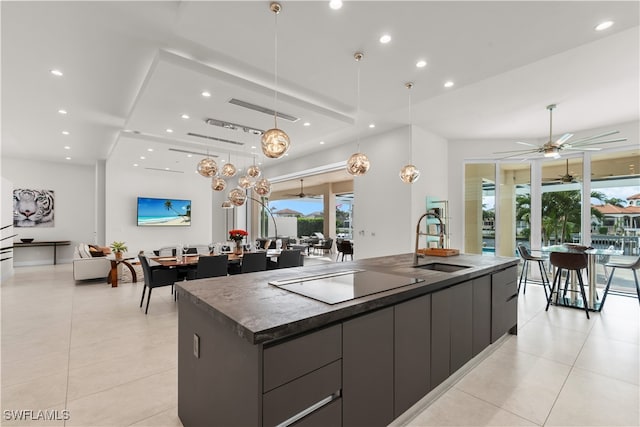 kitchen featuring a large island, ceiling fan, sink, decorative light fixtures, and black electric stovetop