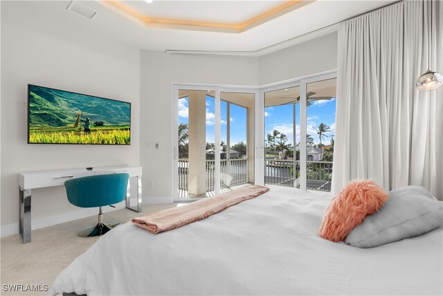 carpeted bedroom featuring access to exterior and a tray ceiling