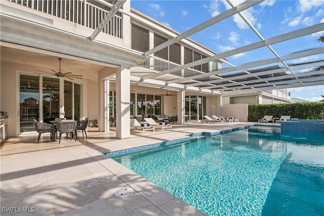 view of pool featuring glass enclosure, ceiling fan, and a patio