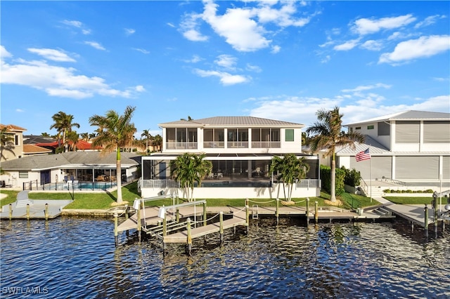 back of house featuring a sunroom, a water view, and a lawn