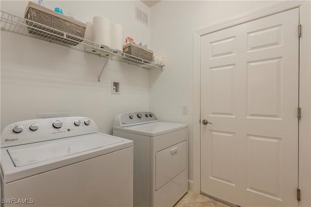 laundry room with washing machine and dryer and light tile patterned floors