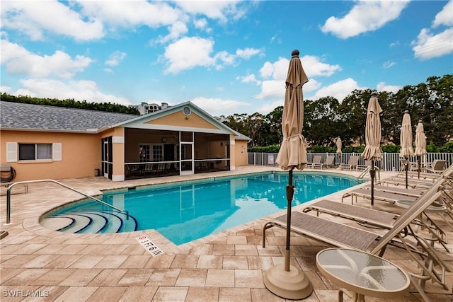 view of swimming pool with a sunroom and a patio