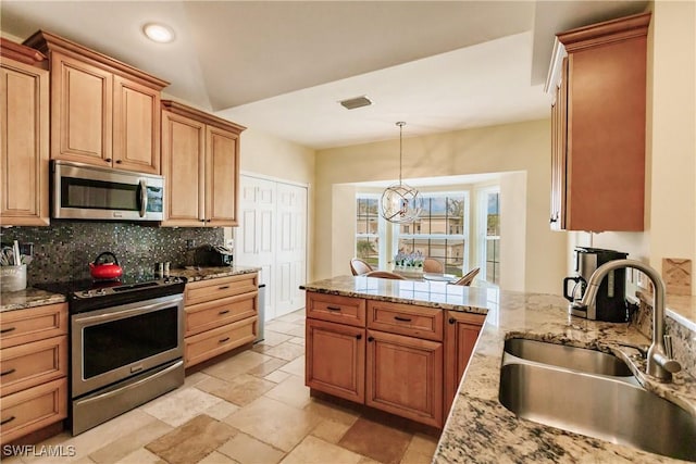 kitchen featuring pendant lighting, sink, decorative backsplash, stainless steel appliances, and a chandelier