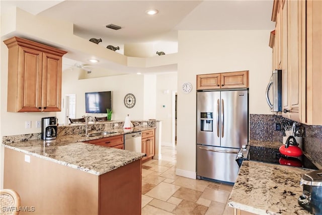 kitchen with light stone counters, sink, kitchen peninsula, and stainless steel appliances