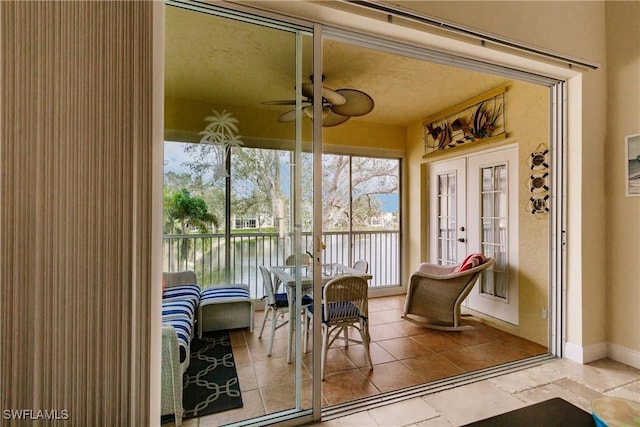 sunroom / solarium with ceiling fan, a water view, and french doors