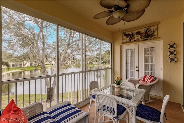 sunroom / solarium featuring ceiling fan, a water view, and french doors