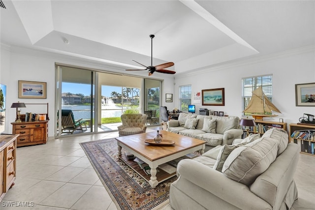 tiled living room featuring ornamental molding, a water view, a wealth of natural light, and a tray ceiling