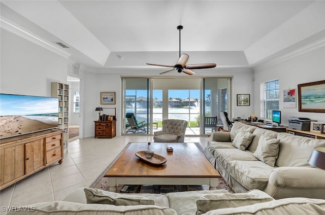 tiled living room featuring a raised ceiling, ornamental molding, and a wealth of natural light