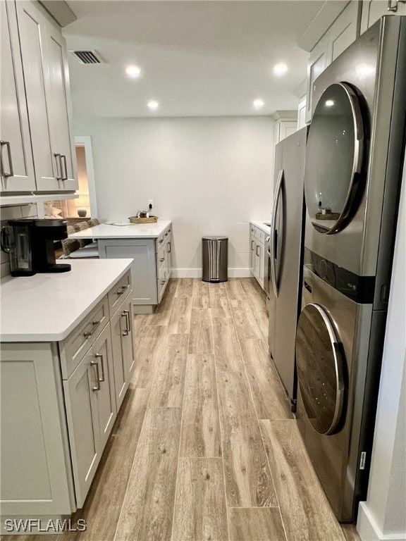 washroom featuring stacked washer and dryer and light wood-type flooring