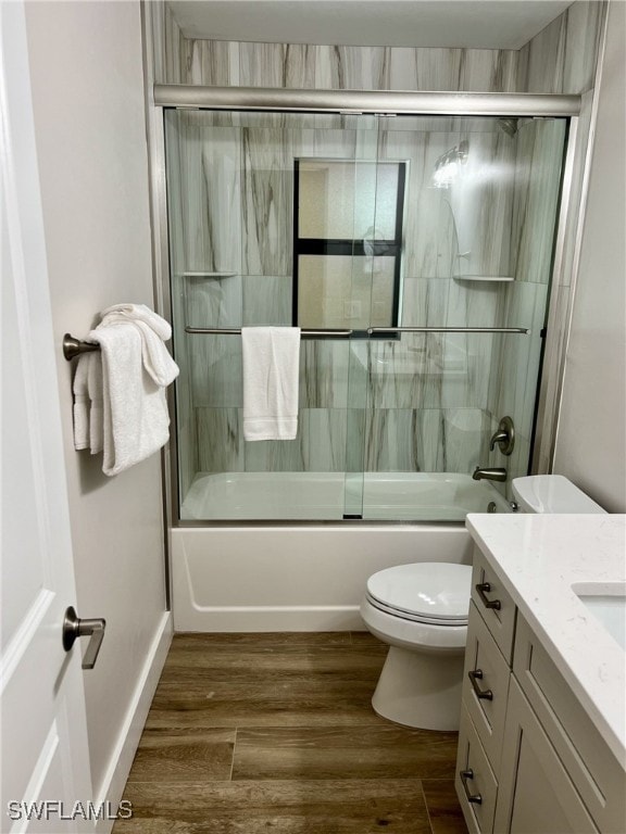 full bathroom featuring wood-type flooring, vanity, toilet, and enclosed tub / shower combo