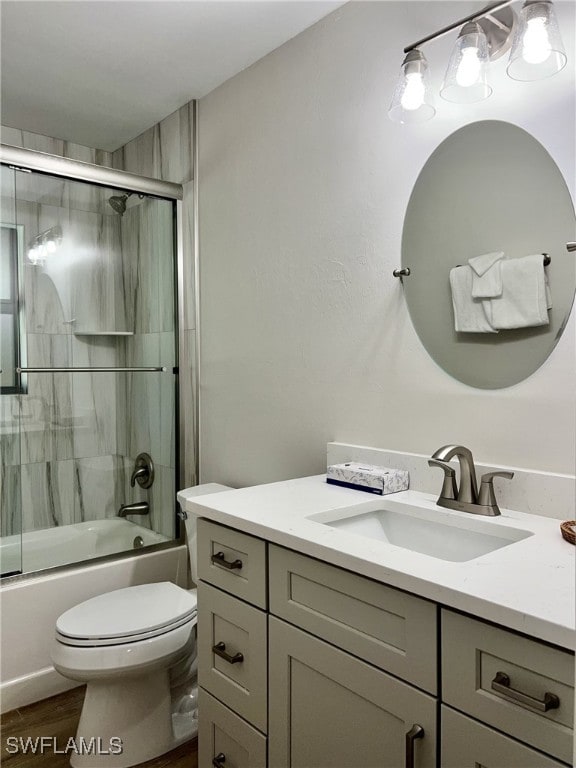 full bathroom with wood-type flooring, vanity, toilet, and bath / shower combo with glass door