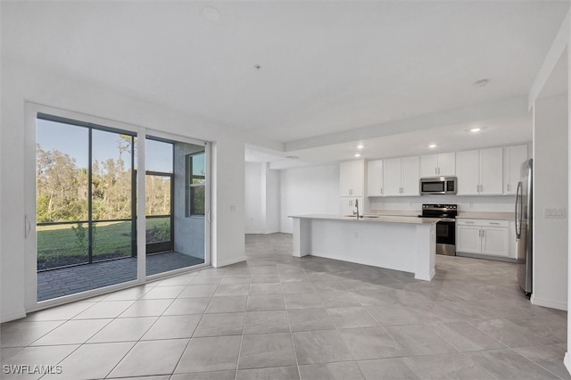 kitchen with a center island with sink, white cabinets, sink, appliances with stainless steel finishes, and light tile patterned flooring