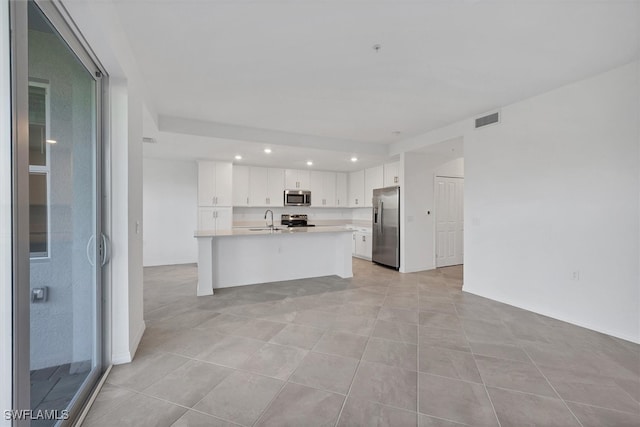 kitchen featuring white cabinetry, sink, stainless steel appliances, a center island with sink, and light tile patterned flooring