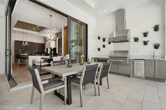 dining area with a raised ceiling, sink, light tile patterned floors, and a chandelier