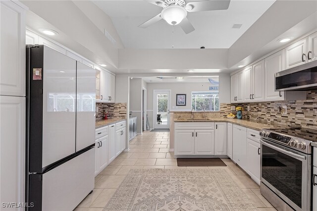 kitchen with white cabinets, sink, light tile patterned floors, kitchen peninsula, and stainless steel appliances