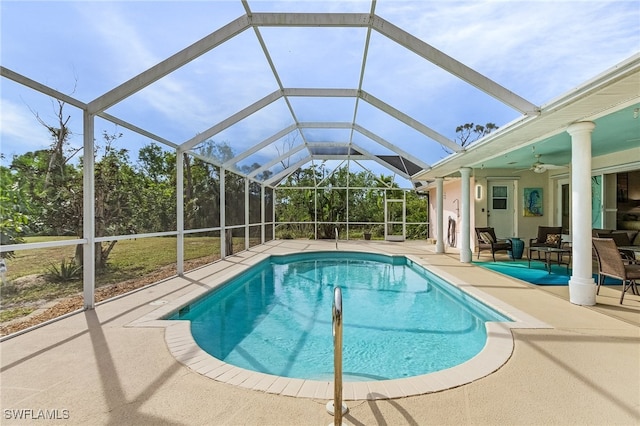 view of swimming pool with glass enclosure, ceiling fan, and a patio