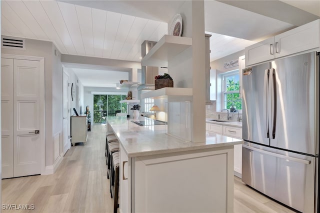 1051 3rd St S Unit 201, Naples, FL 34102 - kitchen featuring freestanding refrigerator, a sink, black electric cooktop, light stone counters, and white cabinets