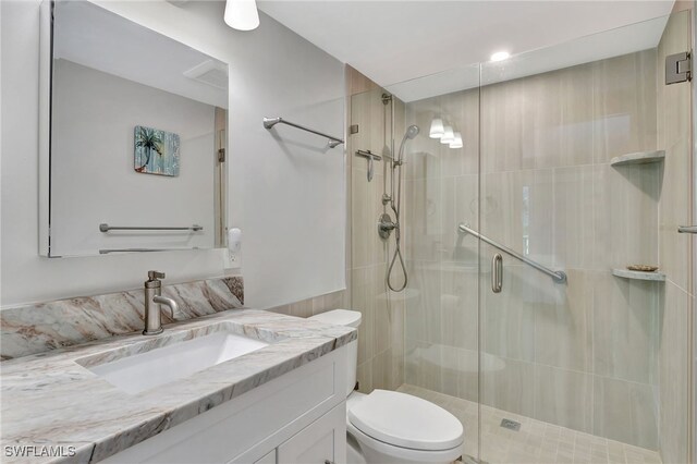 bathroom featuring vanity, toilet, and a shower with door