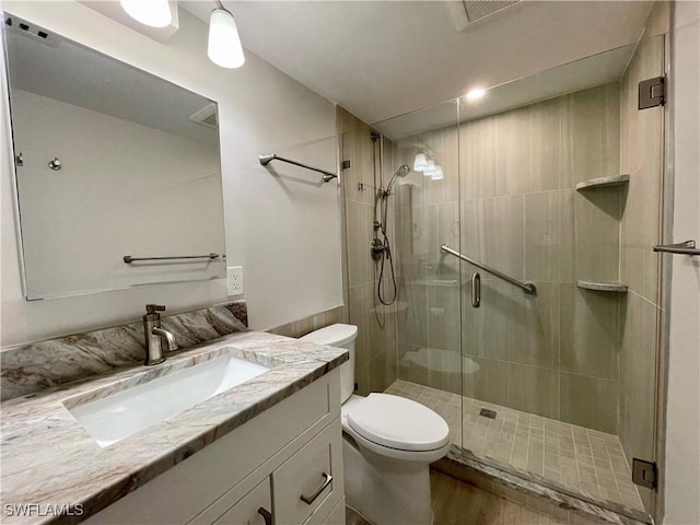 bathroom featuring vanity, an enclosed shower, hardwood / wood-style flooring, and toilet