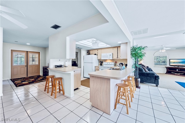 kitchen featuring kitchen peninsula, a kitchen breakfast bar, white appliances, and ceiling fan