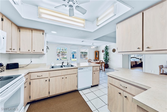 kitchen featuring kitchen peninsula, light brown cabinetry, white appliances, and sink