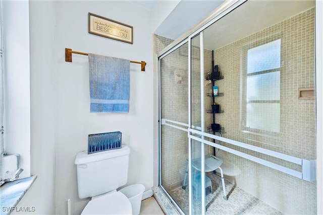 bathroom featuring a shower with shower door and toilet