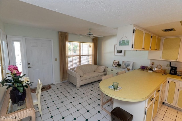 kitchen featuring light countertops, visible vents, open floor plan, a textured ceiling, and a peninsula