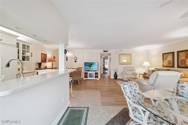 living room featuring light hardwood / wood-style floors, ornamental molding, sink, and an inviting chandelier