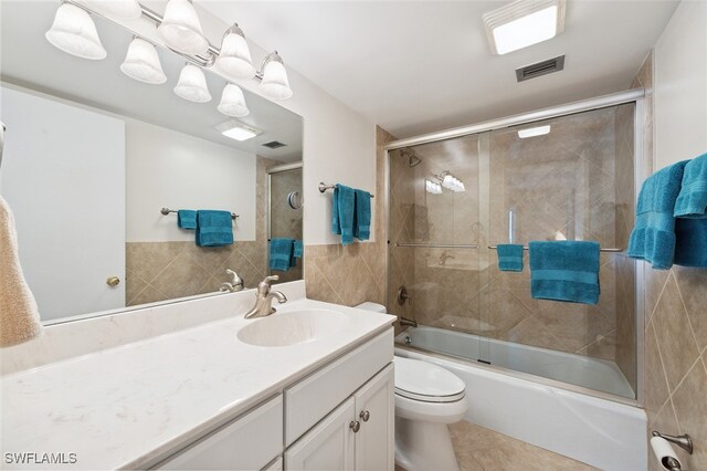 full bathroom with vanity, tile walls, enclosed tub / shower combo, tile patterned flooring, and toilet